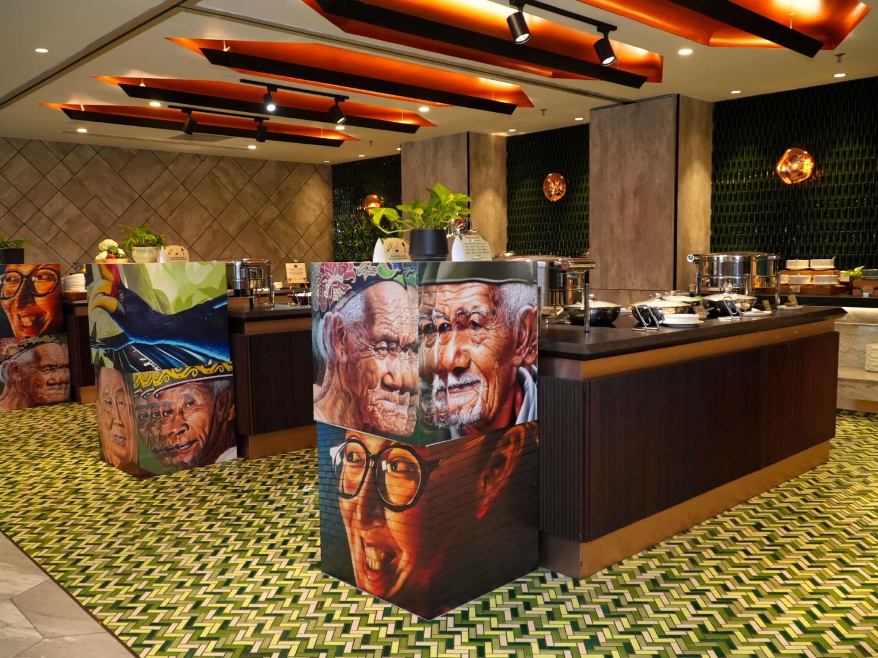 A modern hotel lobby with a central reception desk, decorative wall art, and a patterned floor.