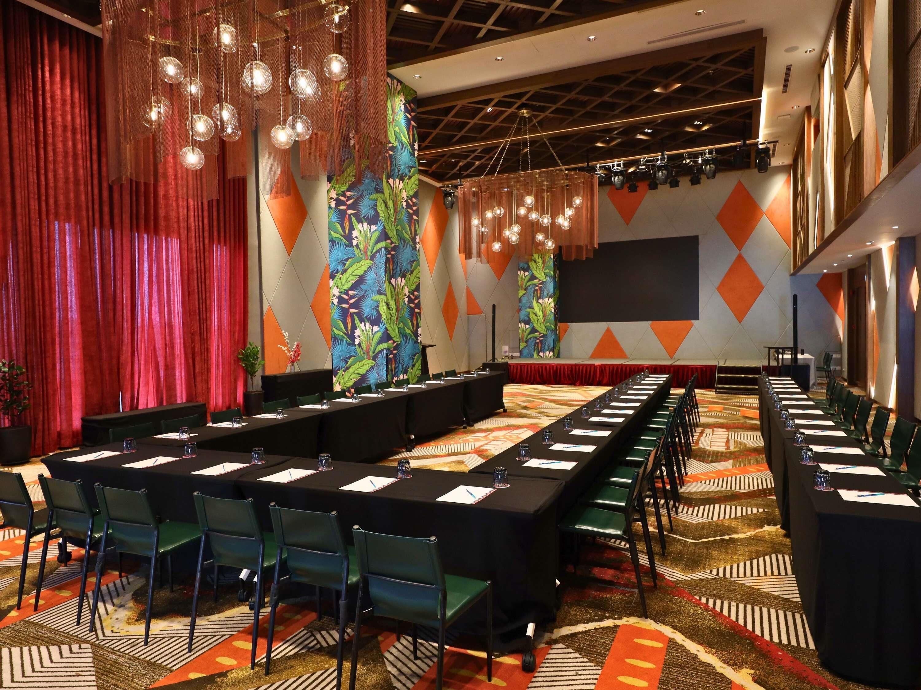 A conference room with a long table, chairs, and a projector screen.