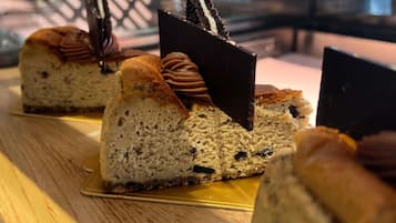 Una porción de pastel de queso con cobertura de chocolate y galletas, sobre un plato dorado.