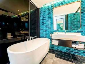 A modern bathroom with a freestanding bathtub, a large mirror, and a vanity with a sink.