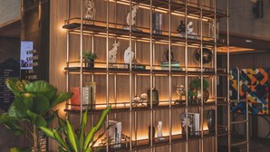 A wooden bookshelf with various decorative items and books, a potted plant, and a sign with room names.