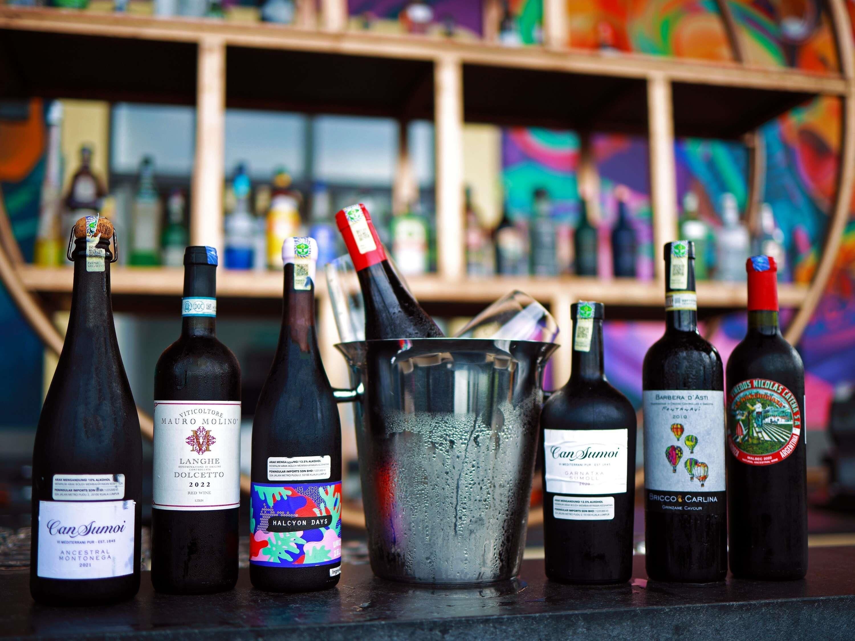 A selection of wine bottles and a metal bucket on a counter.
