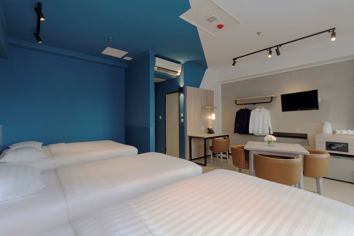 Une chambre d’hôtel avec deux lits, un bureau, une chaise, une télévision et une kitchenette.
