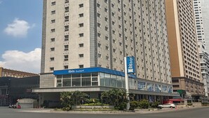 Un edificio de hotel alto y rectangular con fachada azul y blanca, varios pisos y una entrada destacada con marquesina de vidrio.