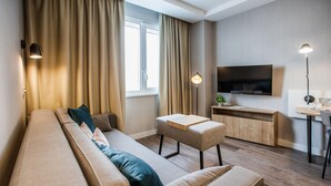 A modern living room with a sofa, ottoman, and a small table with a lamp. - Adagio Kyiv Beresteiska (Kyiv)