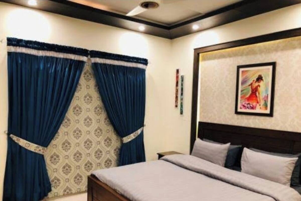 Ein Schlafzimmer mit Bett, Vorhängen, einer Wand mit Muster und einem gerahmten Bild.