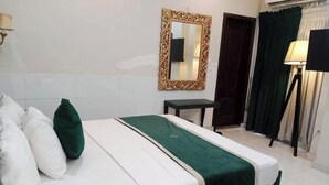 Ein Hotelzimmer mit einem Bett, einem kleinen Tisch, einem Spiegel und einer Lampe.
