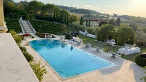 Un espace piscine offrant une vue dégagée sur le paysage environnant, avec un escalier menant à une terrasse et un jardin bien entretenu.