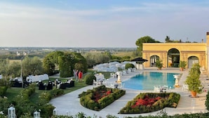 A poolside area with tables and chairs, surrounded by well-maintained gardens and a view of the countryside. - Tenuta Bagni de Consoli 24 (Bertinoro)