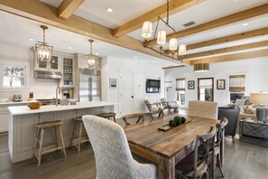 A spacious kitchen with a central island, wooden beams, and pendant lighting. - Walk to Beach | Carriage House (Inlet Beach)