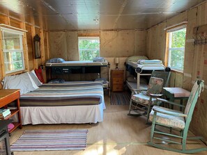 A cabin with two bunk beds, a desk, a chair, and a small table.