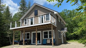 Een twee verdiepingen tellend huis met een overdekte veranda, grote ramen en een grindpad.