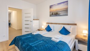 A hotel room with a bed, a nightstand, a painting, and a door leading to another room. - Vacation apartment by the sea, vacation on the island of Usedom, Apartment PLATAN V (Świnoujście)