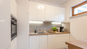 A modern kitchen with white cabinets, a stainless steel oven, a sink, and a window above the countertop. - Vacation apartment by the sea, vacation on the island of Usedom, Apartment PLATAN V (Świnoujście)