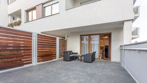 An outdoor patio with grey tiles, a wooden fence, and a sliding glass door leading to a room. - Vacation apartment by the sea, vacation on the island of Usedom, Apartment PLATAN V (Świnoujście)