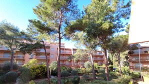 A residential area with multi-story buildings, lush greenery, and a well-maintained garden. - Air-conditioned apartment 3 minutes' walk from the beach and shops (Bormes-les-Mimosas)