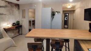 A modern kitchen with a wooden dining table, chairs, a ceiling fan, and a refrigerator. - Air-conditioned apartment 3 minutes' walk from the beach and shops (Bormes-les-Mimosas)