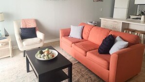 A living room with a sofa, armchair, and coffee table. - Ocean Getaway - Ocean Front Condo (North Topsail Beach)
