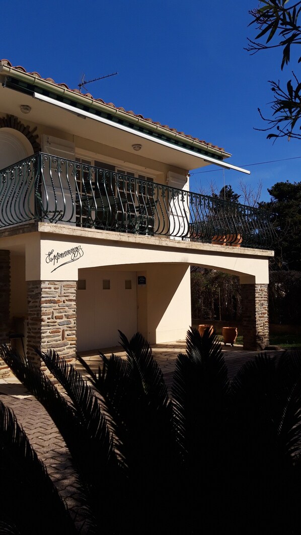 Une maison à deux étages dotée d’un balcon, d’une façade en pierre et d’une enseigne sur laquelle on peut lire « Expérience ».