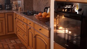 Una cocina con armarios de madera, una campana extractora negra, horno de acero inoxidable y suelo de baldosas.