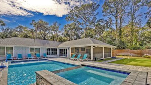 A pool area with two separate pools, lounge chairs, and a covered seating area.