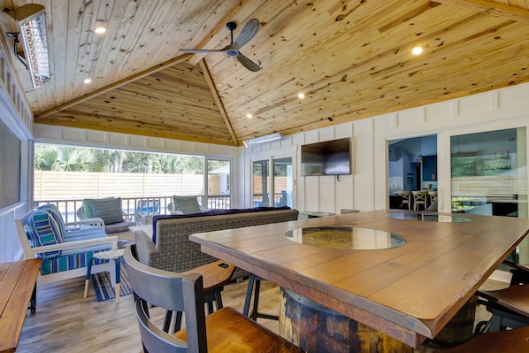 A spacious outdoor area with a wooden ceiling, a large bar area, and seating arrangements.