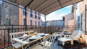 An outdoor patio with a table set for breakfast, white chairs, and a covered seating area. - Florella Residences Studio terrasse Maréchal Joffre (Cannes)