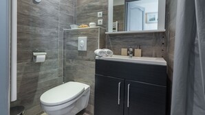 A modern bathroom with a shower, toilet, and dark cabinetry. - Florella Residences Studio terrasse Maréchal Joffre (Cannes)