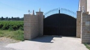 Una entrada protegida con un portón de metal y un muro de ladrillo.