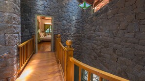 A stone-walled hallway with wooden railings and a wooden floor. - Mystic Mayapott Thekkady (Idukki)