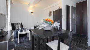 Un comedor moderno con una mesa de madera oscura, sillas blancas y un jarrón con flores naranjas.