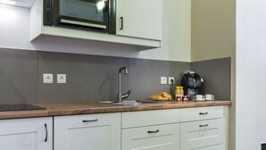 Una cocina equipada con microondas, cafetera y pileta.