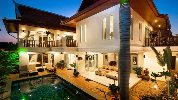 A two-story house with a swimming pool, multiple balconies, and a well-lit interior.