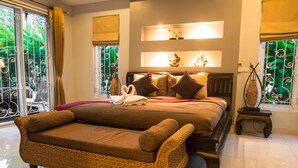 A spacious bedroom with a large bed, a wicker sofa, and a small side table.