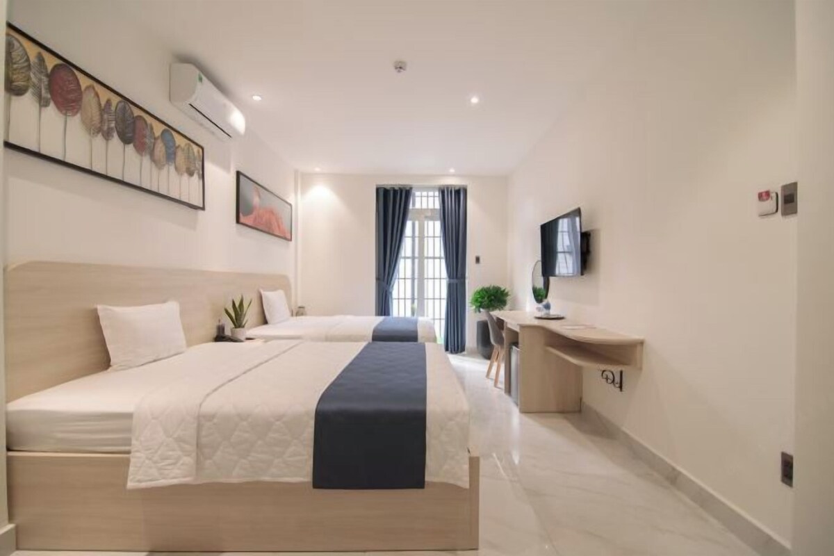 A hotel room with a large bed, a desk, and a TV.
