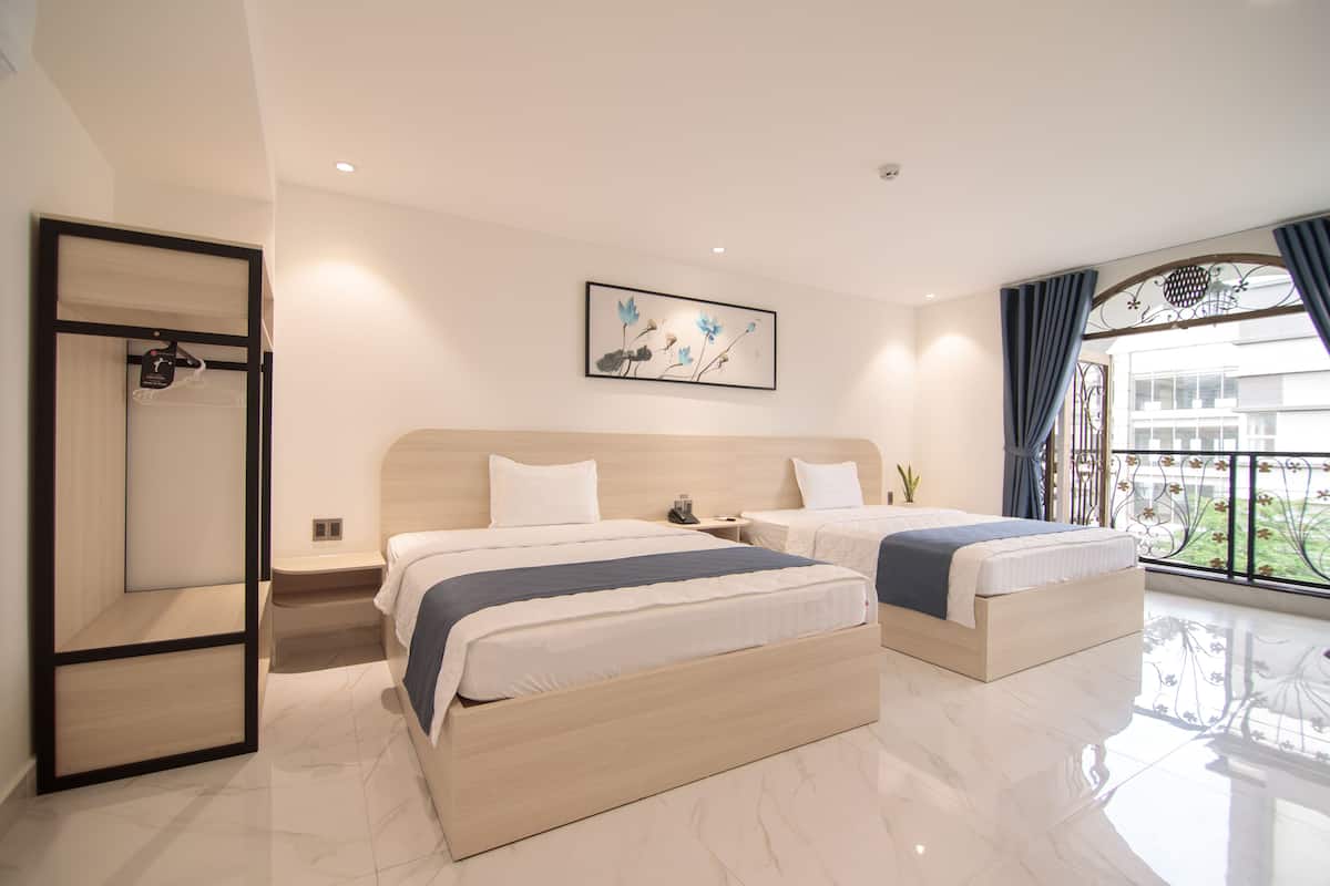 Quarto de hotel com duas camas, um guarda-roupa, um quadro e uma varanda com vista.