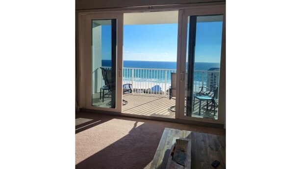 A balcony with a view of the ocean, featuring a wooden deck and outdoor furniture.