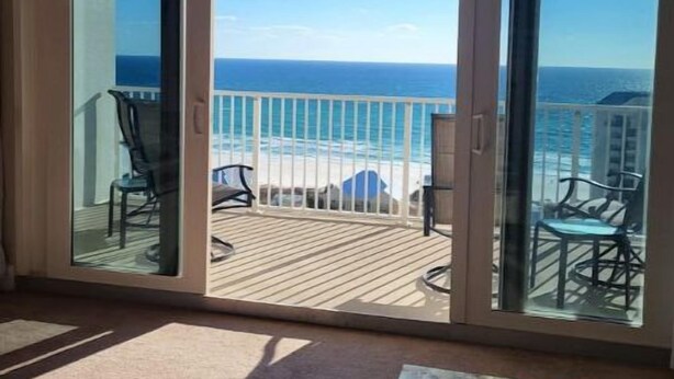 Un balcón con vista al océano, que incluye una terraza de madera y mobiliario exterior.