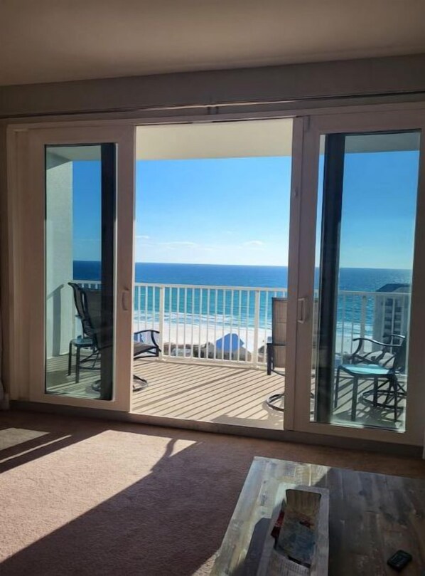 Un balcón con vista al océano, que incluye una terraza de madera y mobiliario exterior.