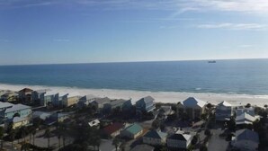 A coastal town with buildings near the beach and a ship in the distance.