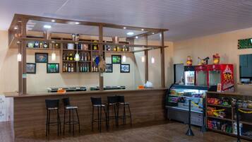 Uma área de bar com prateleiras de madeira, banquetas e um refrigerador.