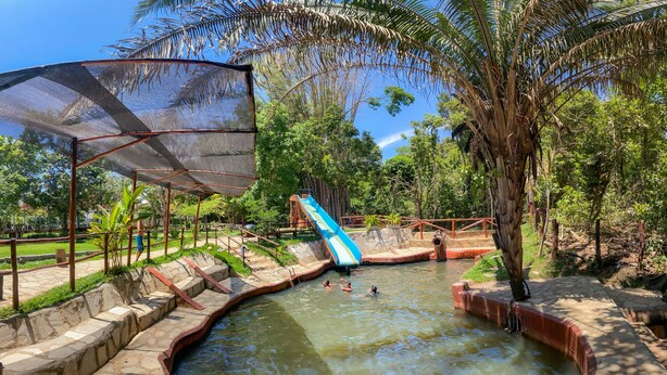 A water park with a pool, a slide, and a shaded area. - Clube Pousada Chácara da Isabel (Águas Lindas de Goiás)