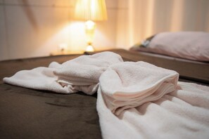 Ein ordentlich bezogenes Bett mit einem gefalteten weißen Handtuch daneben.