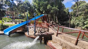 A water feature with a blue slide and a wooden bridge over a pond. - Clube Pousada Chácara da Isabel (Águas Lindas de Goiás)