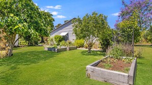 Un giardino curato con una casa di legno, aiuole rialzate e una varietà di piante.