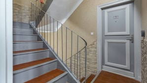 Una escalera con barandillas de metal que lleva a una puerta con una placa numérica.