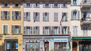 Una hilera de edificios con varios escaparates, incluyendo un letrero visible de 'RIVIERA LINES' y 'LAVERIE DU PORT'.