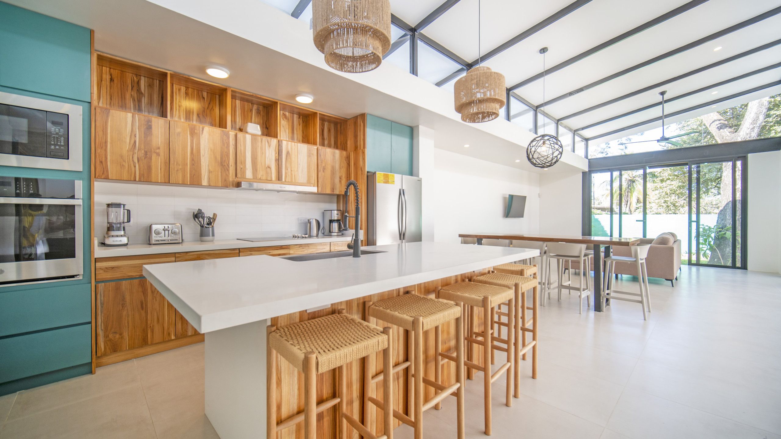 A modern kitchen with wooden cabinets, a large island with bar stools, and a dining area with a table and chairs.