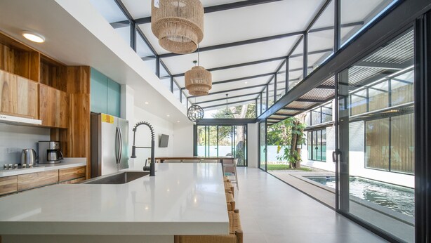 Una cocina moderna con una isla grande, electrodomésticos de acero inoxidable y vistas a una fuente exterior.