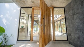 A modern interior with large glass doors, a concrete ceiling, and a stone wall.
